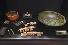 an assortment of ancient items on display in a museum case, including toothbrushes and combs