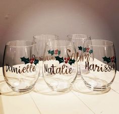 four wine glasses sitting on top of a table with holly and red berries painted on them