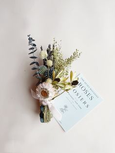 a bouquet of flowers sitting on top of a white table next to a book with writing