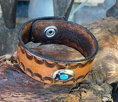 a close up of a leather bracelet on a piece of wood with metal eyeballs