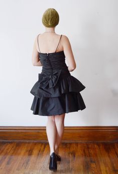 "Description: Black party dress with a drop waist and ruffled skirt. zips up the back and has a large decorative bow. Some tulle under the skirt for fullness. Bodice has boning up the sides. Measurements of garment, allow space for fit. Bust: 32\" some some gathers for cup space. Shown on 36\" and it was way too snug. Waist: 28\" Hips: Open Length: 37\" Skirt length: 15\" I take my measurements flat, and double for circumference. Tag: No brand, just an ILGWU label. Fabric: Polyester Condition: E Party Mini Dress With Ruffle Hem And Fitted Bodice, Party Dress With Ruffled Tiered Skirt, Elegant Tiered Skirt Mini Dress For Party, Vintage Dresses With Ruffles For Gala, Party Dress With Ruffle Hem And Fitted Bodice, Party Mini Dress With Bow And Fitted Bodice, Fitted Tiered Skirt Dress For Party, Vintage Party Dress With Ruffle Hem, Vintage Ruffle Mini Dress For Party