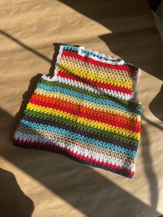 a multicolored crocheted blanket laying on the floor