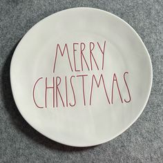 a white plate with the words merry christmas written on it, sitting on a gray surface