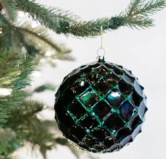 an ornament hanging from a christmas tree with green and black ornaments on it