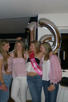 four beautiful young women standing next to each other in front of a giant number six balloon