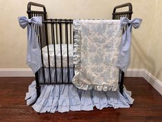 a baby crib with blue ruffled bedding and matching blanket