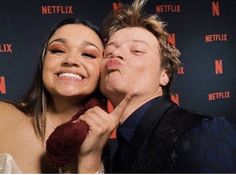 a man and woman posing for a photo in front of netflix's red carpet