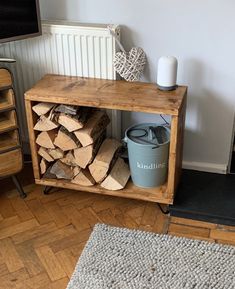 a pile of wood sitting on top of a wooden floor next to a metal trash can