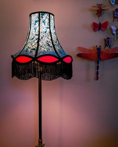 a lamp that is sitting on top of a table next to a wall with dragon wings