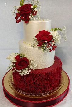 a three tiered wedding cake with red roses on top and baby's breath