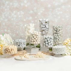 there are many different candies on display in the table with white and yellow flowers