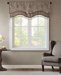 a chair sitting in front of a window next to a table with flowers on it