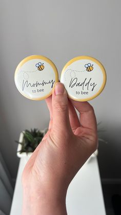 someone holding up two magnets with the words mommy to bee on them