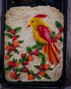 a cake decorated with fruit and vegetables on top of a baking sheet in the shape of a bird