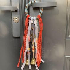 a door handle with bells and ribbons hanging from it's side on a metal door