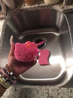 a person is holding up a hello kitty soap bar in a stainless steel bathroom sink