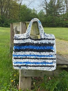 a crocheted tote bag sitting on top of a wooden bench in the grass