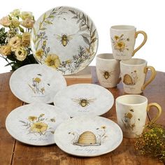 a wooden table topped with plates and cups filled with honeybees painted on them