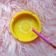 a yellow frisbee with a smiley face painted on it and a pink toothbrush