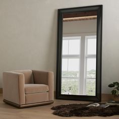 a large mirror sitting on top of a wooden floor next to a chair and potted plant