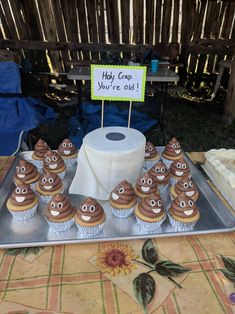 cupcakes with chocolate frosting and googly eyes are on a tray next to a sign that says hey crap you're old