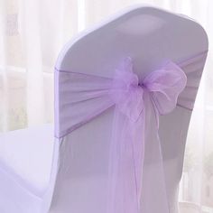 the back of a white chair with purple ribbon