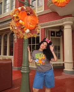 a woman standing next to a pole with a pumpkin decoration on it's head