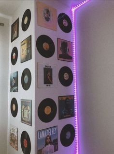 a wall with various records on it and purple light coming from the bottom right corner