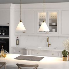 a kitchen with white cabinets and marble counter tops, two pendant lights hanging over the island