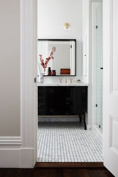 a bathroom with white walls and black vanity in the center, along with a large mirror on the wall