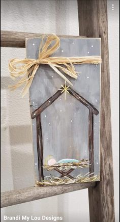 a painting of a nativity scene hanging on a wooden ladder with a star above it