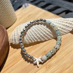 summer themed silver and blue/green handmade beaded bracelet with a starfish bead. Silver Starfish Beaded Bracelet Gift, Silver Starfish Shaped Beaded Bracelet Gift, Silver Beaded Ocean-inspired Bracelets, Silver Beaded Stretch Bracelet For The Beach, Adjustable Silver Beaded Bracelet With Starfish Charm, Silver Beaded Bracelet With Starfish Charm As Gift, Ocean-inspired Silver Beaded Bracelets, Silver Starfish Beaded Bracelets For Beach, Handmade Silver Beaded Bracelets Ocean-inspired