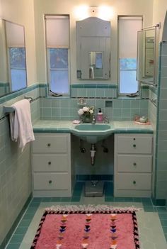 a bathroom with blue tiles and pink rug on the floor in front of two sinks