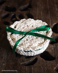 a white crochet dishcloth with green ribbon on it sitting on a wooden surface