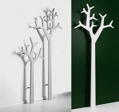 three different types of white trees against a green wall and one is standing in front of the other