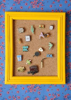 a yellow frame filled with different types of pins and magnets on top of a blue wall