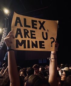 a person holding up a sign that says alex are u mine? at a concert