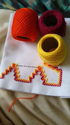 three spools of thread sitting on top of a white cloth next to each other