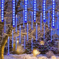 blue lights are hanging from trees in the snow