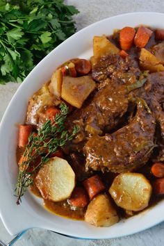 a white plate topped with meat, potatoes and carrots