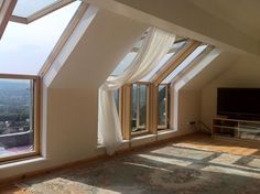 an empty room with large windows and curtains