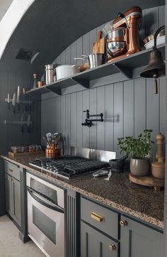 a kitchen with an oven, stove and shelves filled with pots and pans on top of it