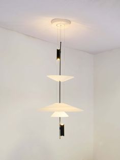 three lights hanging from the ceiling in a room with white walls and wood flooring