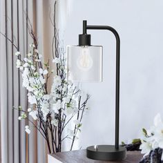 a table lamp sitting on top of a wooden shelf next to a vase with white flowers