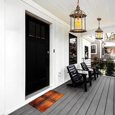 a porch with two black chairs and a light hanging from the ceiling