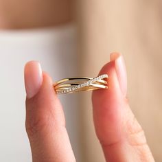 a woman holding a gold ring with diamonds on it's sides and the end of her finger