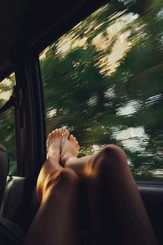 a person is sitting in the back seat of a car with their feet on the dashboard