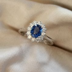 a blue and white diamond ring sitting on top of a beige cloth with diamonds around it