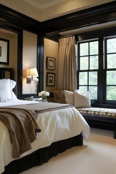 a large bed sitting next to two windows in a room with white carpet and black trim