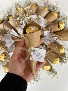 a hand holding a paper cone filled with gold foil and some baby's breath flowers